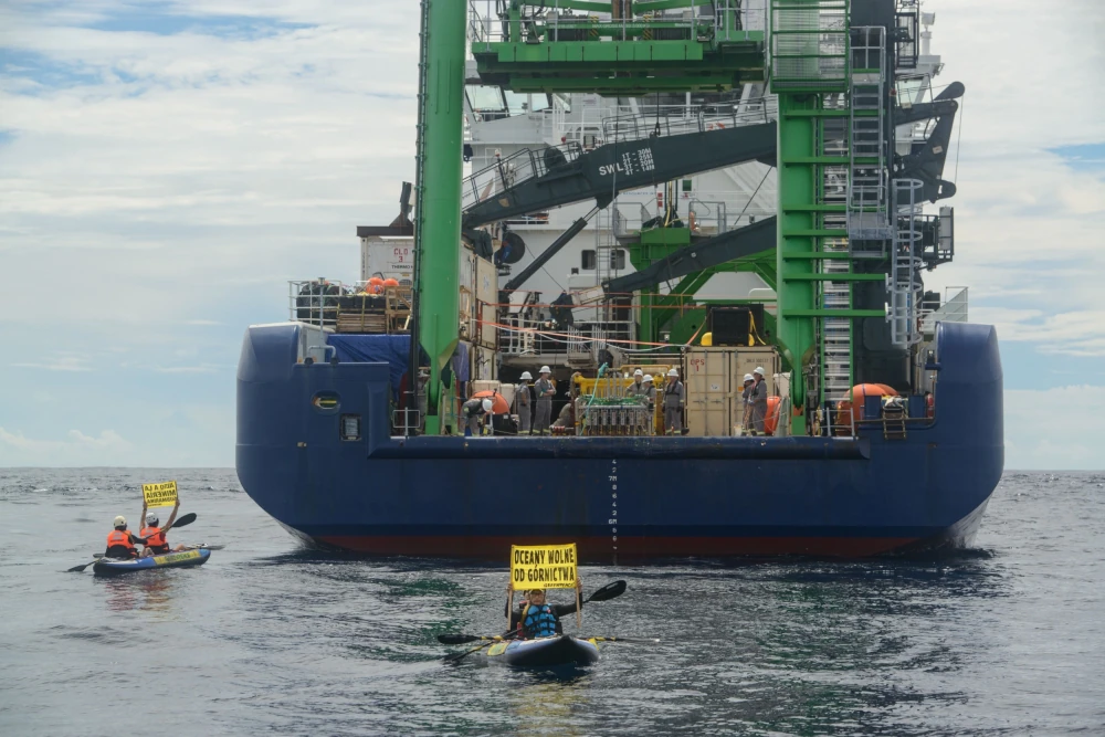 Greenpeace protestors kayak around the MV Coco research vessel